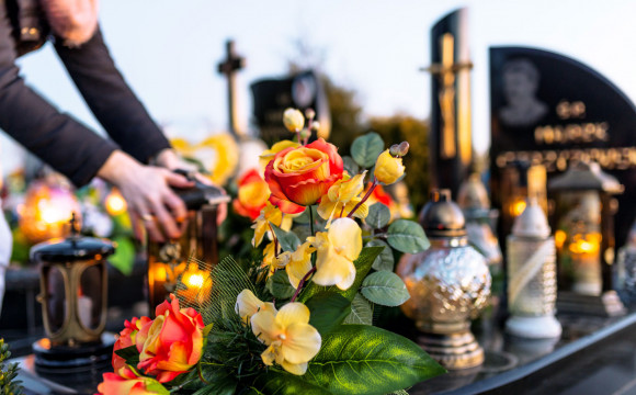 Grob z nagrobnikom, svečami in cvetjem.