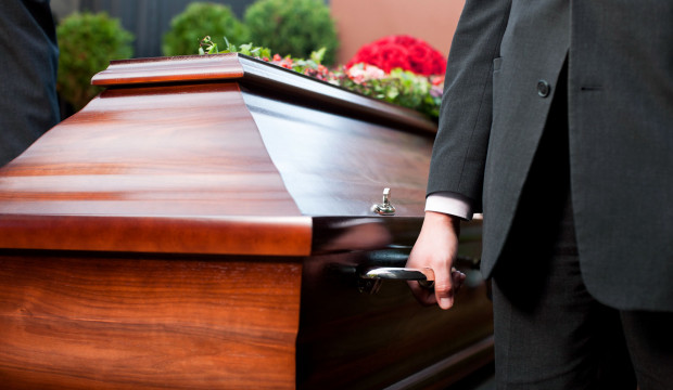 Pogrebnik nosi leseno krsto.